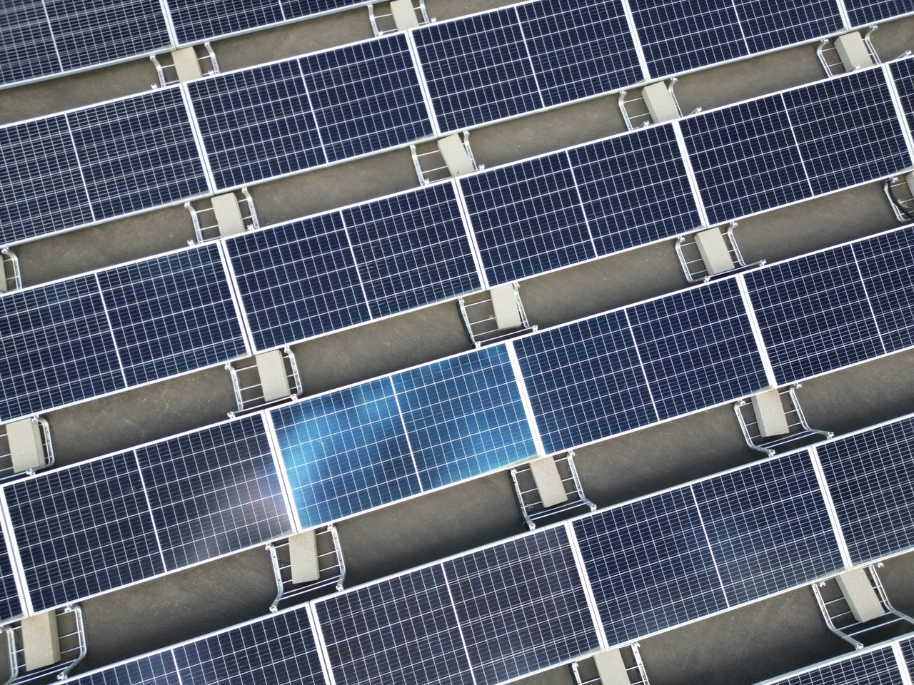 services-02 Aerial view of a large array of solar panels on a rooftop, utilizing renewable energy.